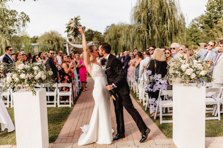 A couple exiting their wedding ceremony in The Gardens at Pillar and Post.