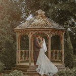 Bride and groom embracing under a wooden gazebo at Millcroft Inn & Spa