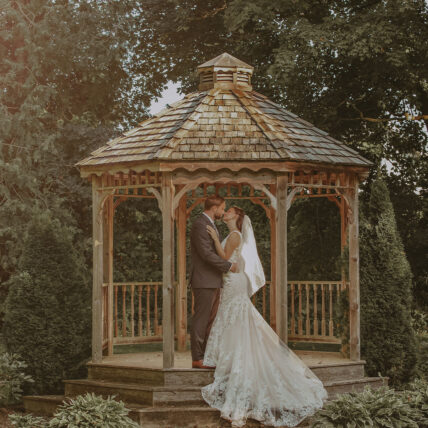Bride and groom embracing under a wooden gazebo at Millcroft Inn & Spa