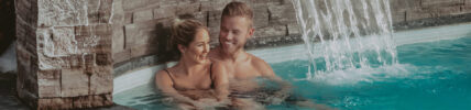 Couple in an outdoor hot springs pool with waterfall at Millcroft Inn & Spa