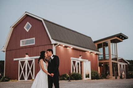 A couple kissing outside the barn at Cave Spring Vineyard in Niagara-on-the-Lake.