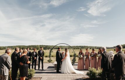 A couple holds hands during a wedding ceremony at Queenston Mile Vineyard in Niagara