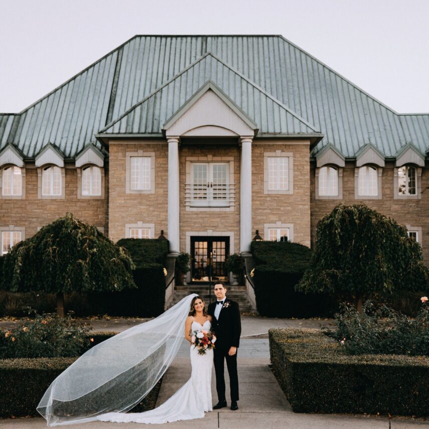 A newly married couple poses outside of Chateau des Charmes a luxury winery wedding venue in Niagara on the Lake