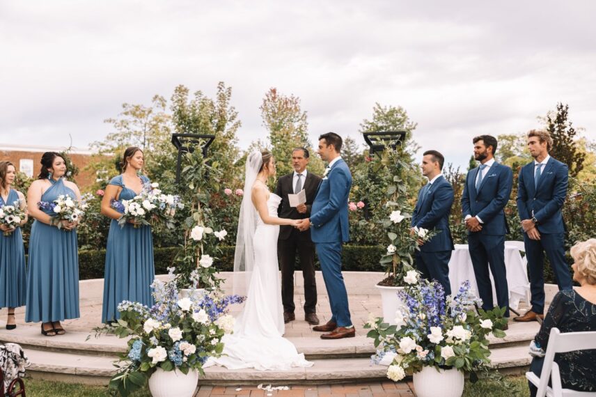 Garden wedding ceremony at La Roserie, Pillar and Post, surrounded by climbing roses and lush seasonal blooms in Niagara-on-the-Lake