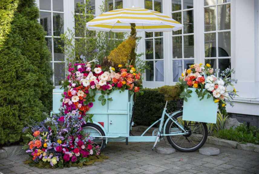 Floral-themed display with decorated cart and flowers at Niagara-on-the-Lake In Bloom workshop area