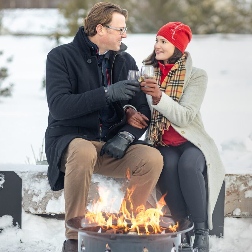 A couple by the fire cheering wine in The Gardens at Pillar and Post during the Vintage Hotels Christmas Market.