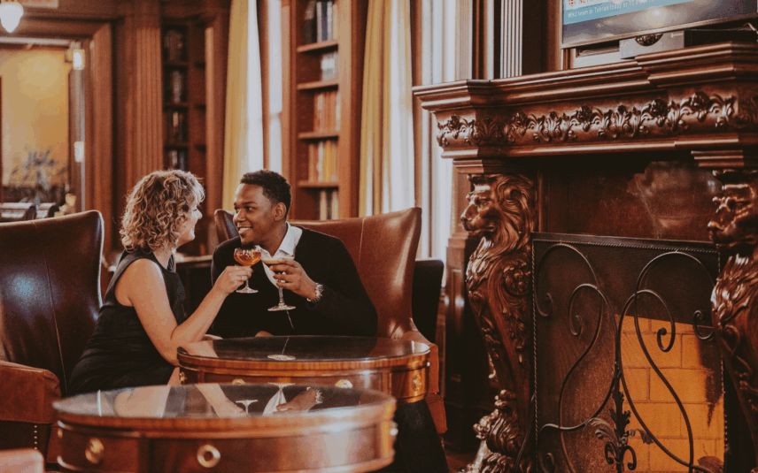Couple enjoying drinks and sitting by fireplace at The Churchill Lounge in the Prince of Wales hotel in Niagara-on-the-Lake.